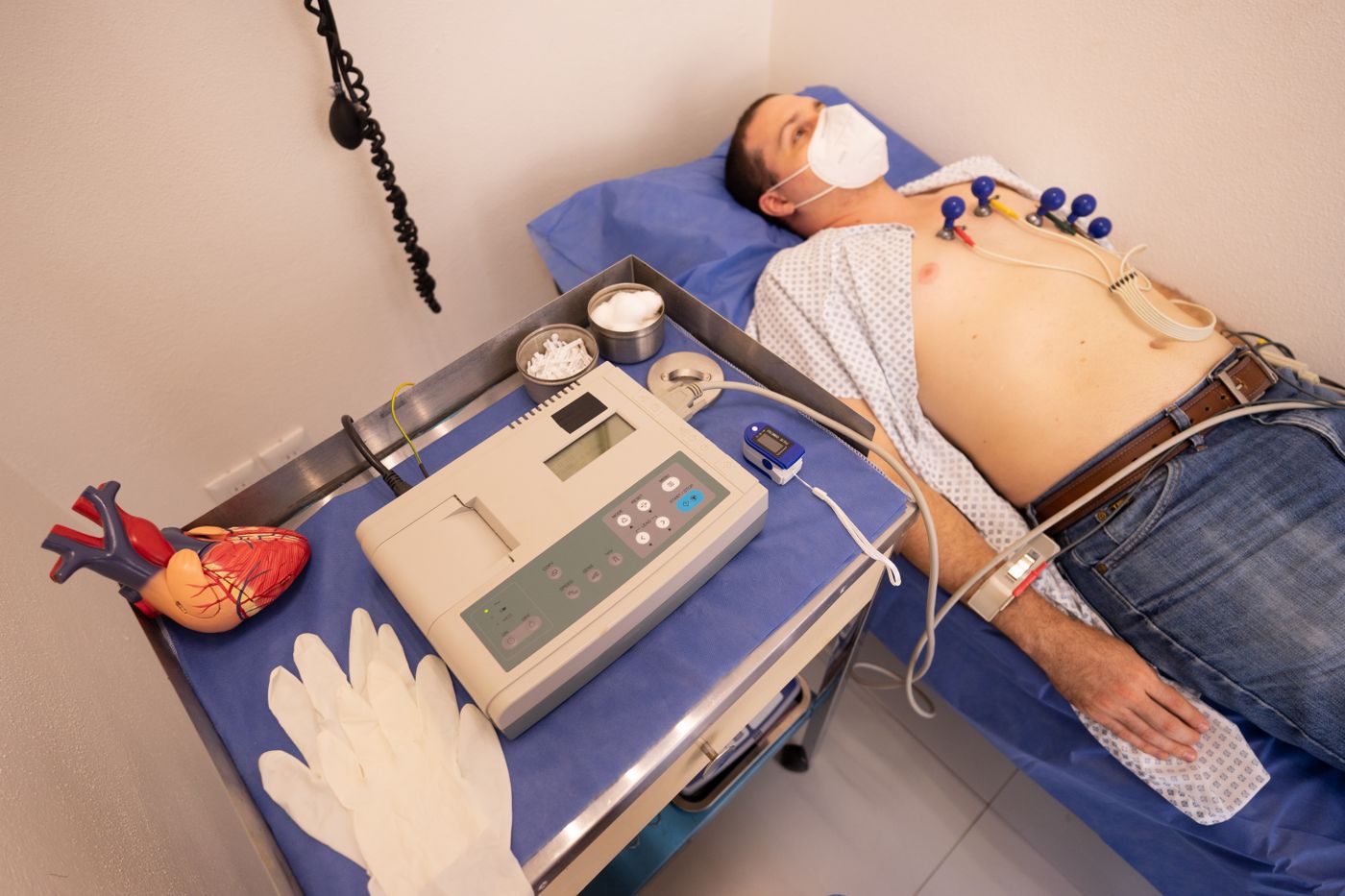 Paciente realiza eletrocardiograma com eletrodos conectados ao equipamento.
